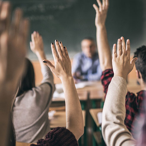 Students raising their hands in a classroom